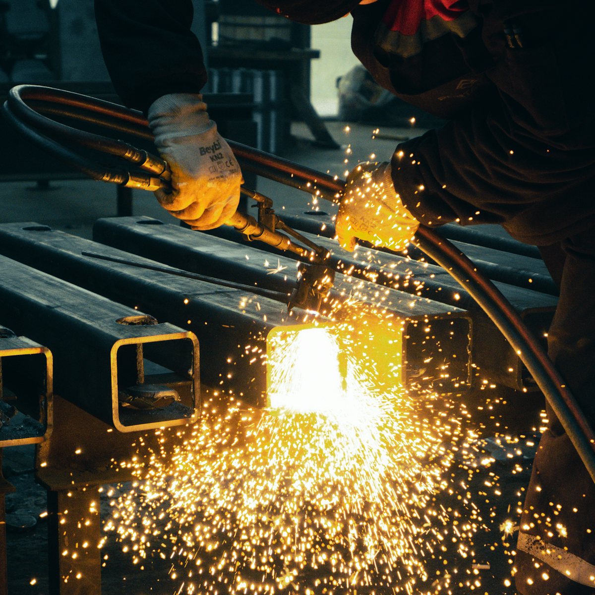 Welder cutting steel box section in the workshop
